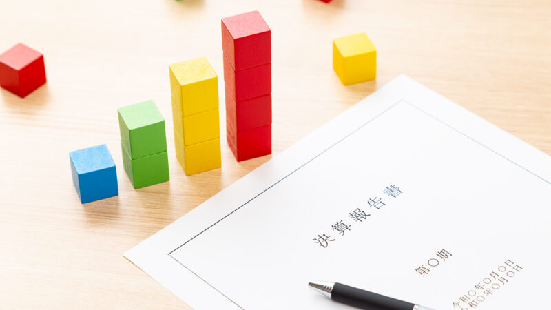 決算報告書とカラフルなブロックで業績を表現するイメージ