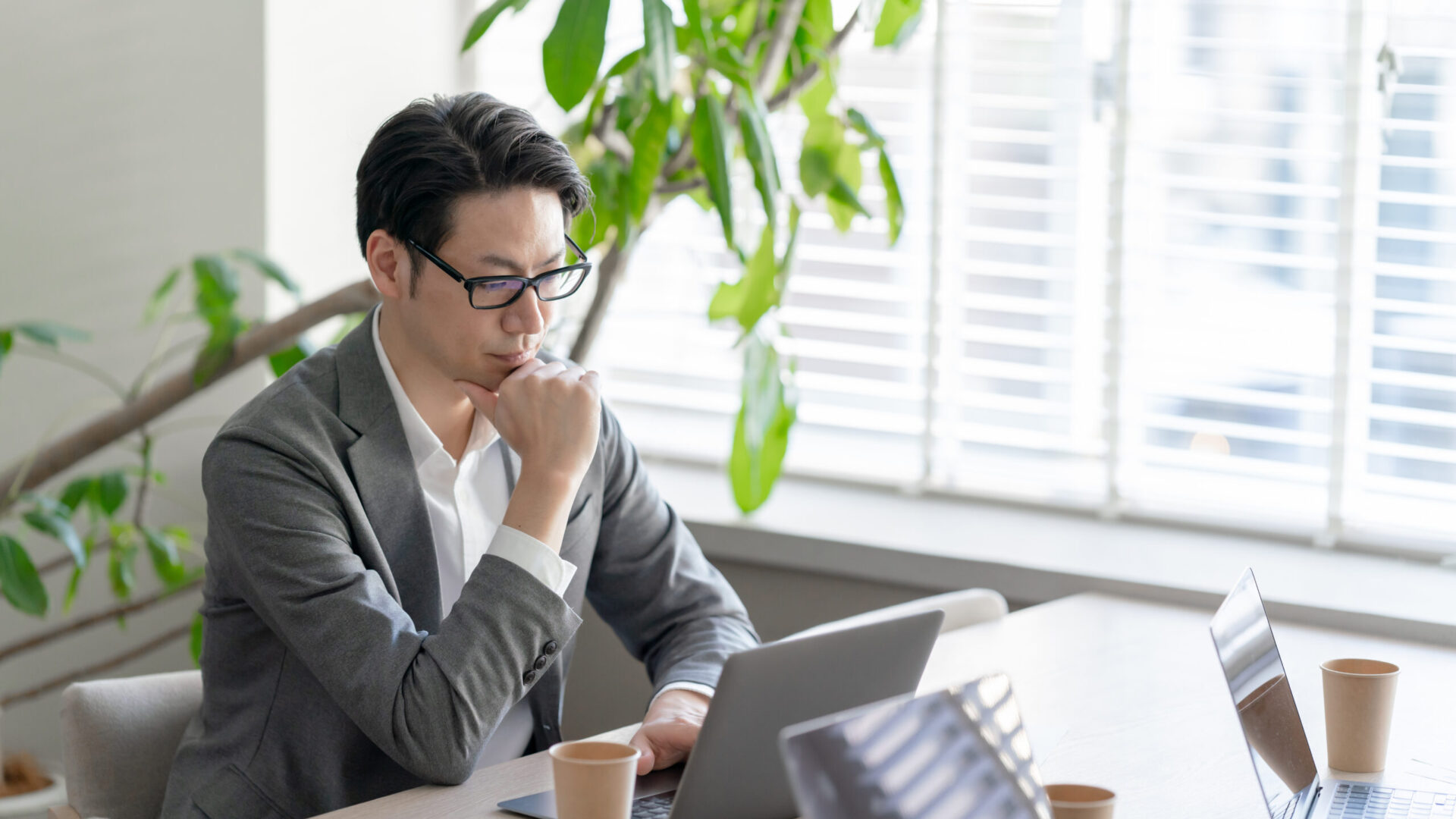 ノートパソコンを前に法人成りのタイミングを検討する男性個人事業主