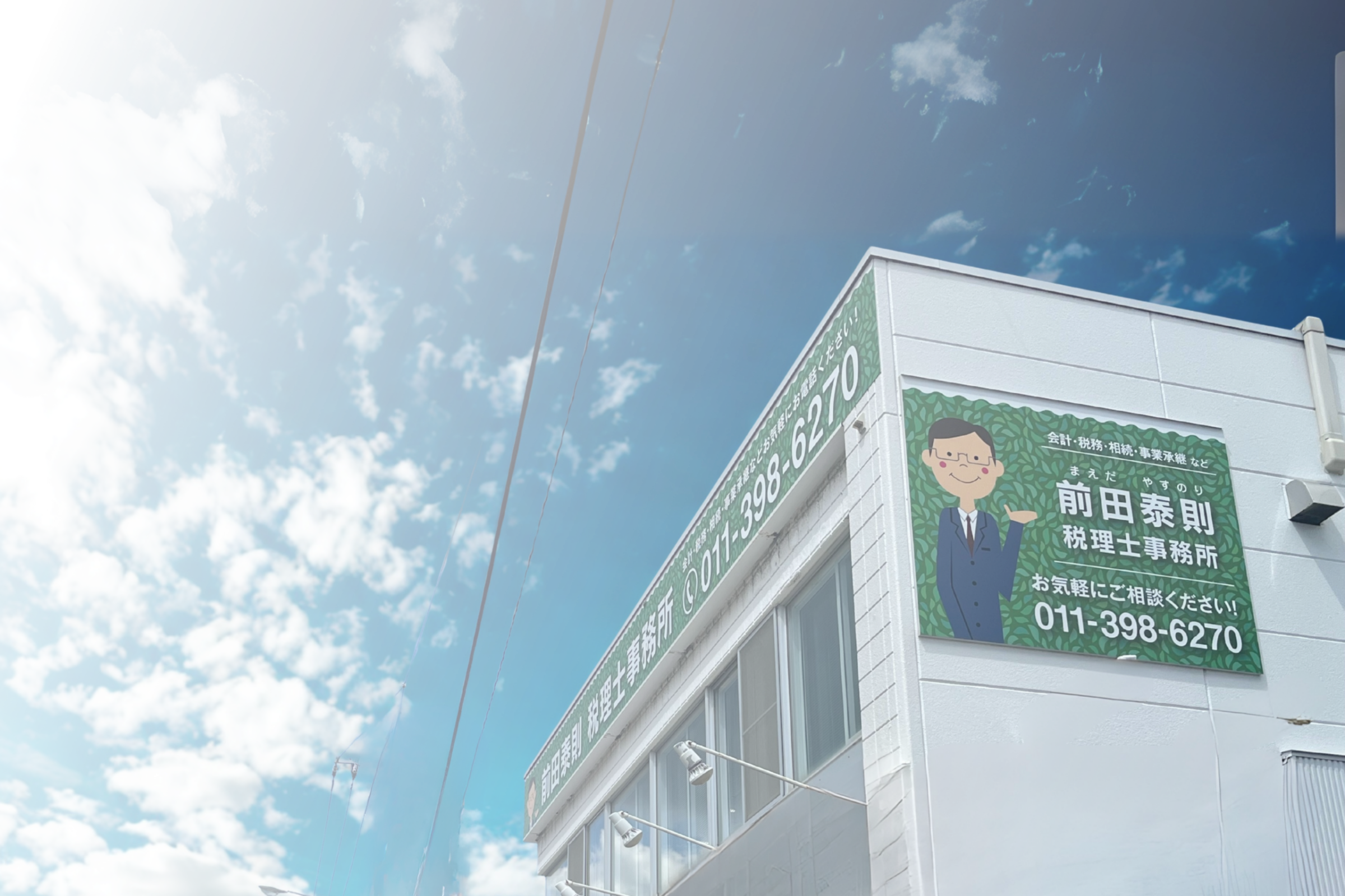 札幌市の前田泰則税理士事務所の外観。緑色の看板に事務所名と似顔絵が描かれている。