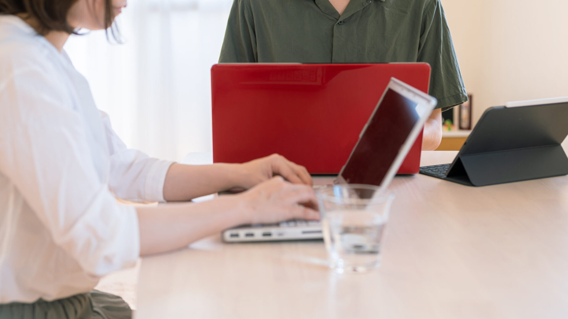 自宅のテーブルでパソコンを使いながら家計や事業の数字を一緒に確認する夫婦