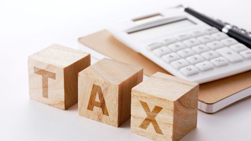 木製ブロックのTAXと電卓が置かれた税金計算イメージ