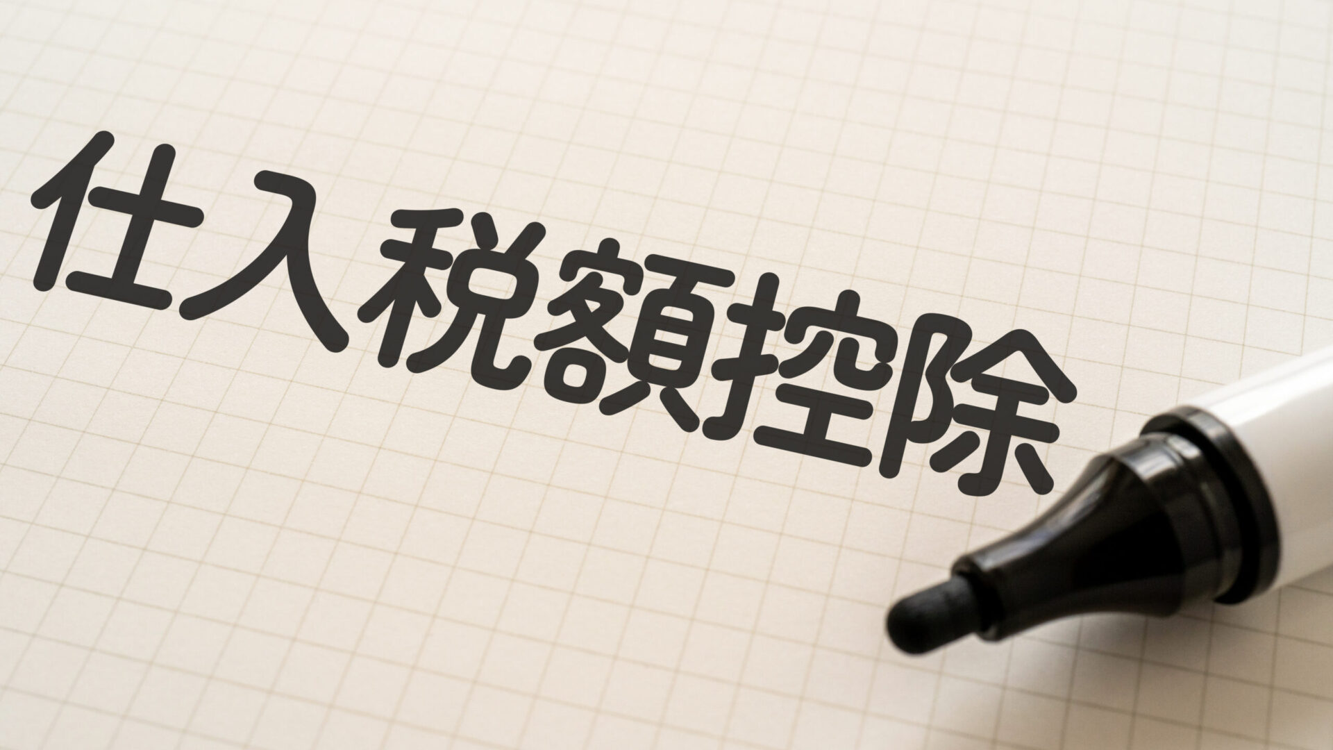 仕入税額控除の文字が方眼用紙に太字で書かれているイメージ。右下に黒いマーカーが置かれている。