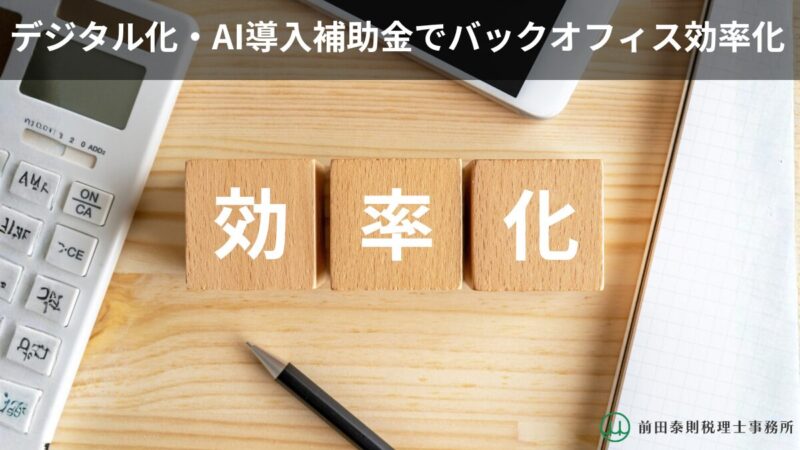 木目のデスク上に「効率化」と書かれた木製ブロックが並び、電卓・スマホ・ペン・ノートが置かれている。上部に「デジタル化・AI導入補助金でバックオフィス効率化」の文字。