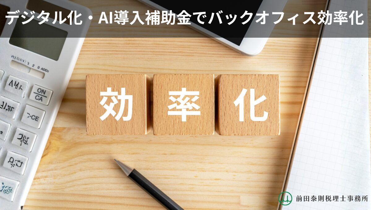 木目のデスク上に「効率化」と書かれた木製ブロックが並び、電卓・スマホ・ペン・ノートが置かれている。上部に「デジタル化・AI導入補助金でバックオフィス効率化」の文字。